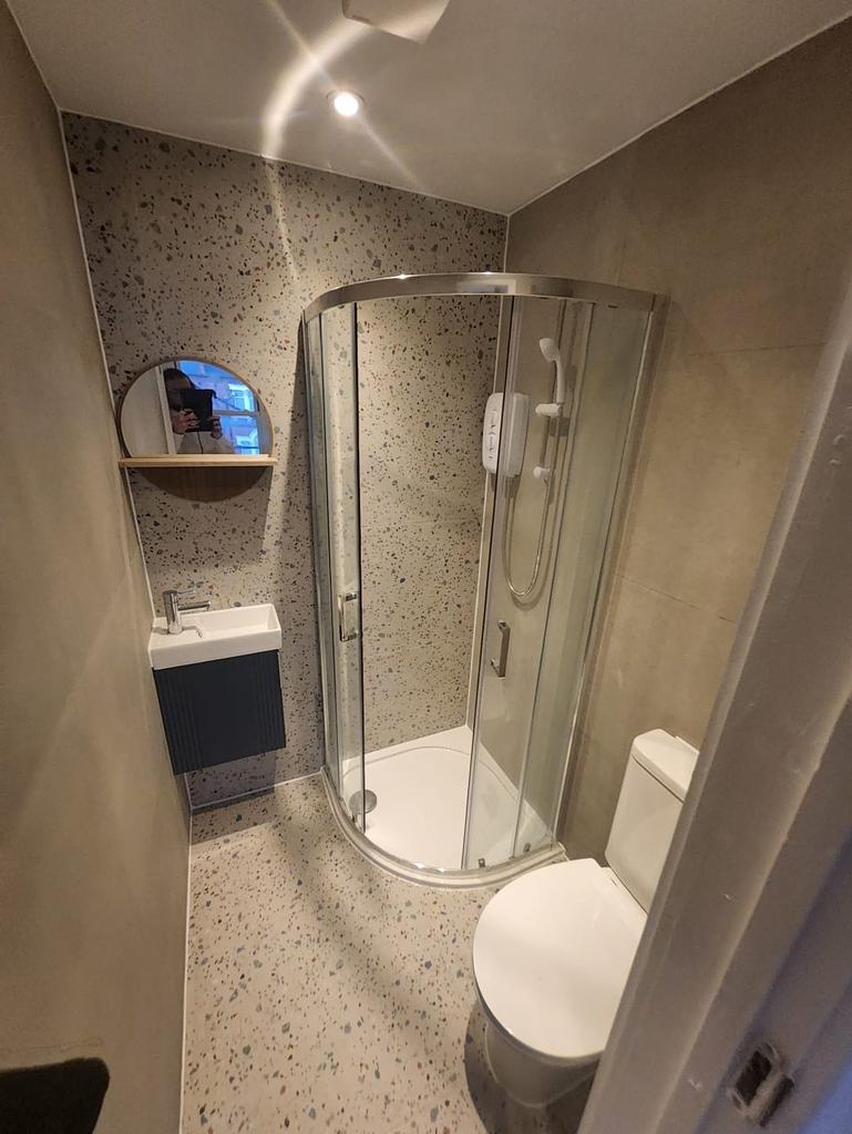 Modern compact bathroom with curved shower...