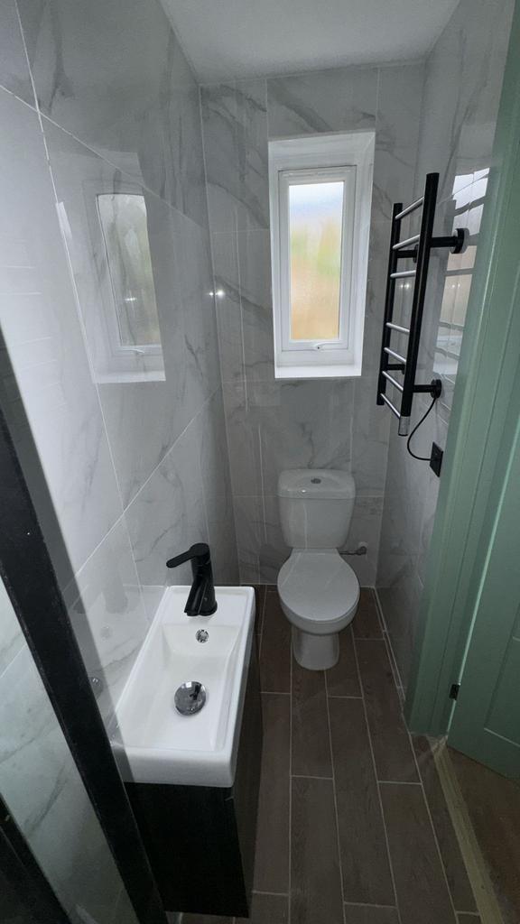 Modern tiled bathroom with compact sink and toi...