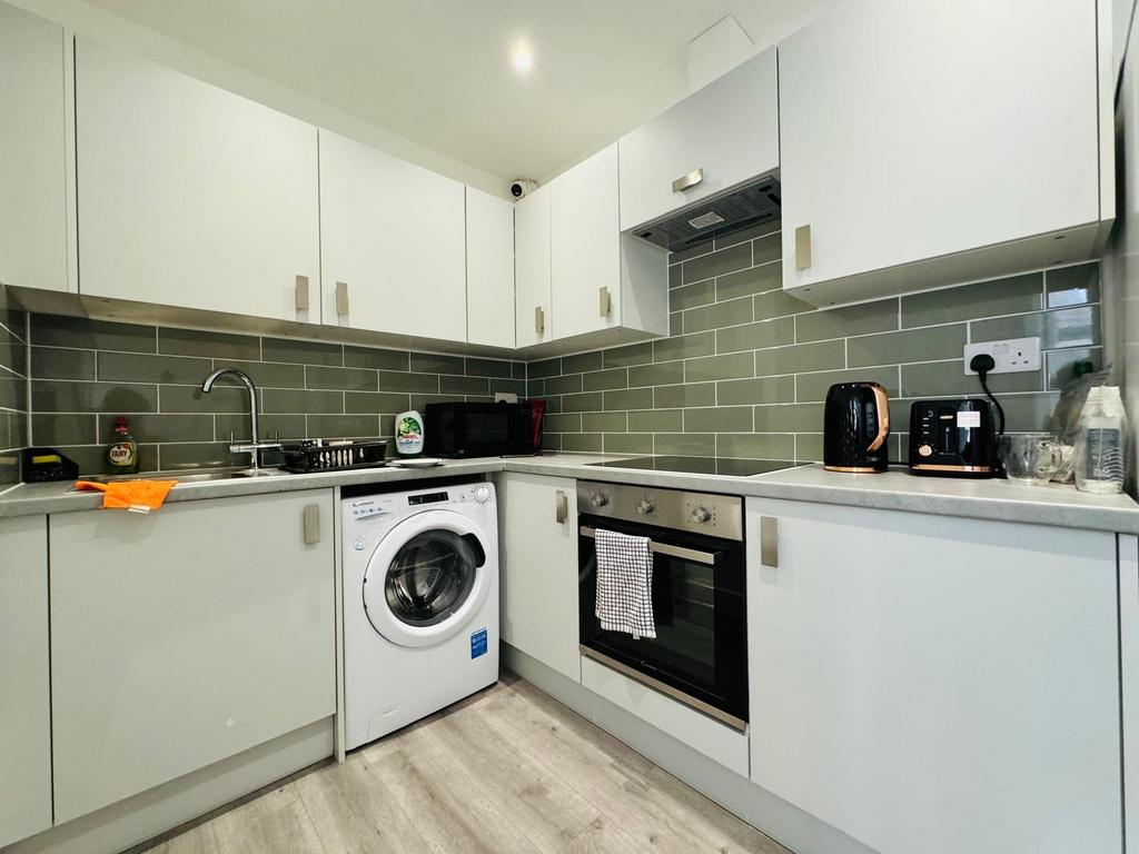 Modern fitted kitchen with appliances and tiled...