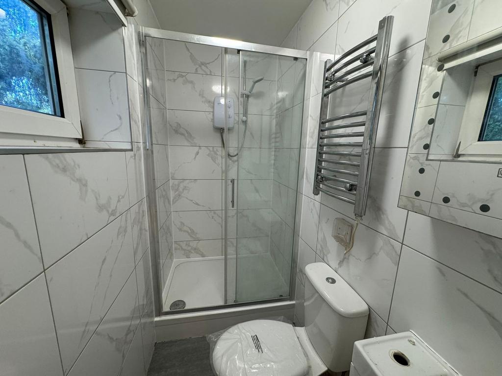 Modern tiled bathroom with glass shower and hea...