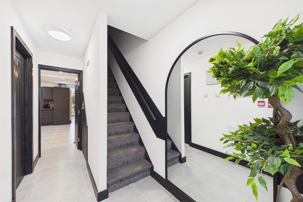 Bright modern hallway with staircase and mirror...