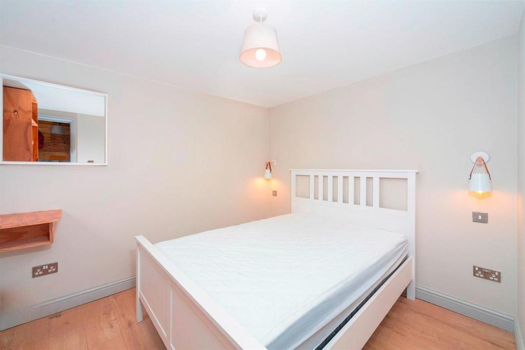 Bright, tidy bedroom with white bed frame...