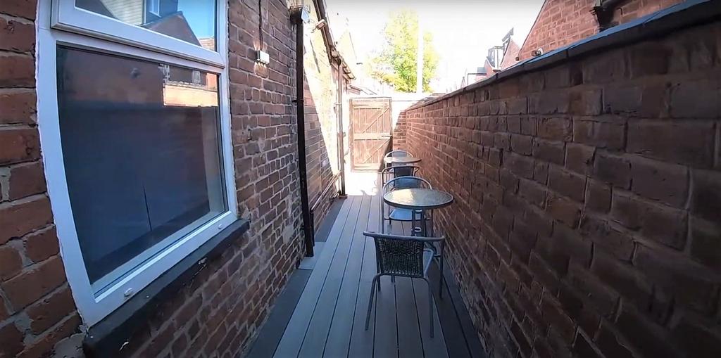 Narrow outdoor terrace with seating and brickwa...