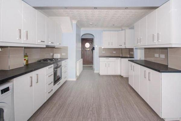 Bright, modern galley kitchen with white cabine...
