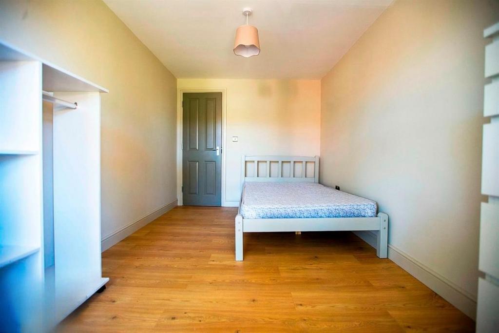 Bright, simple bedroom with wooden floors...