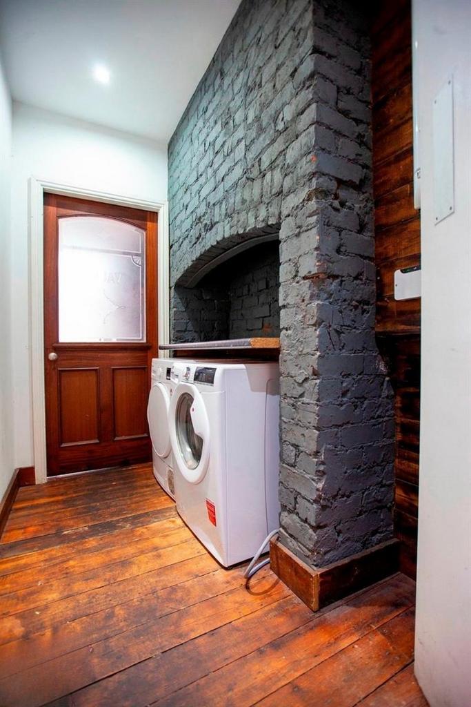 Stylish utility area with washer and rustic bri...