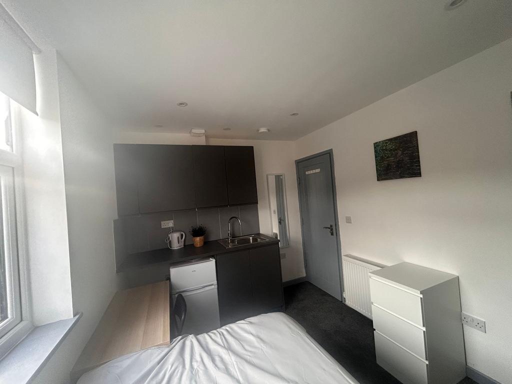 Compact room with kitchenette and desk by windo...