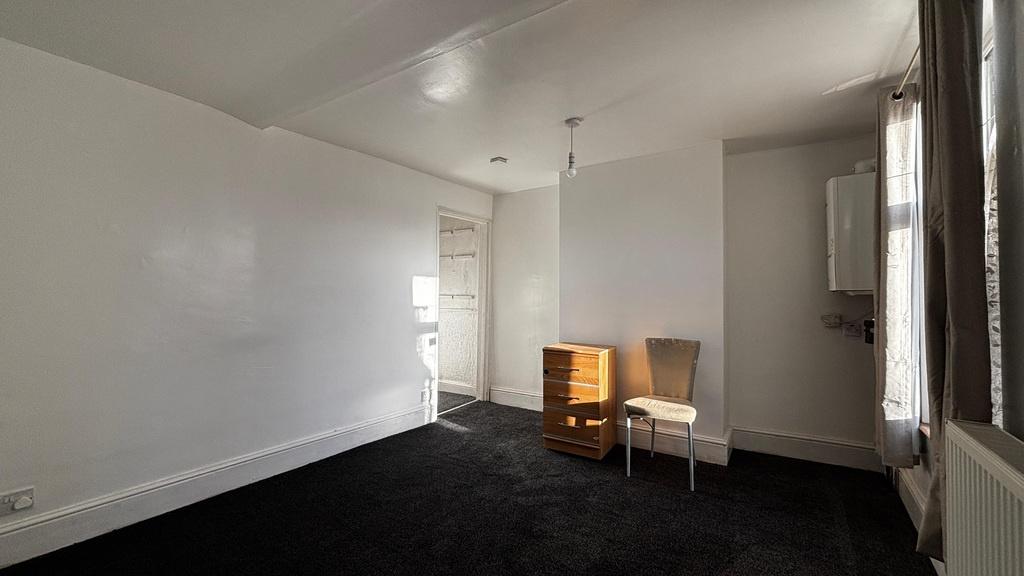 Bright, neutral double bedroom with black carpe...