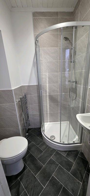 Modern tiled bathroom with curved shower cubicl...