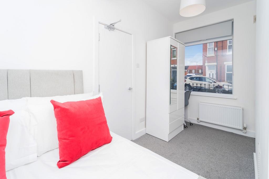 Bright, neat bedroom with bold accent cushions...