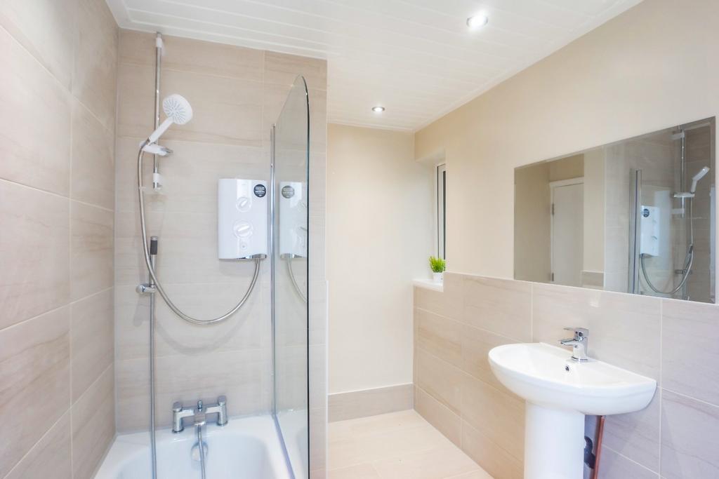 Bright modern bathroom with shower over bath...