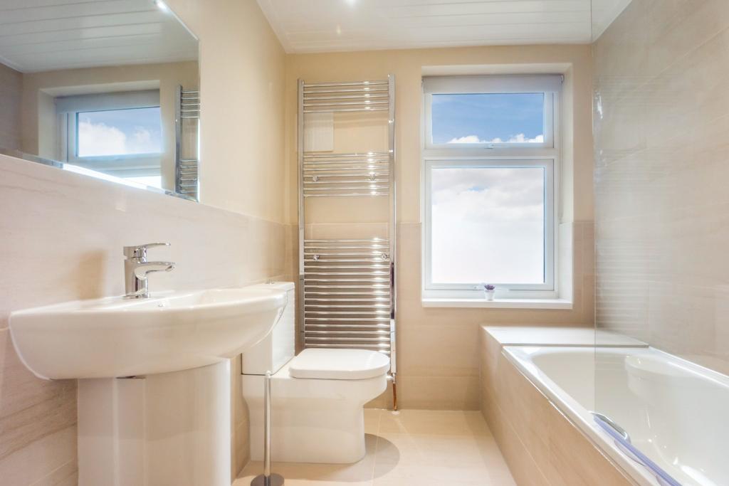 Bright modern bathroom with bath and towel warm...