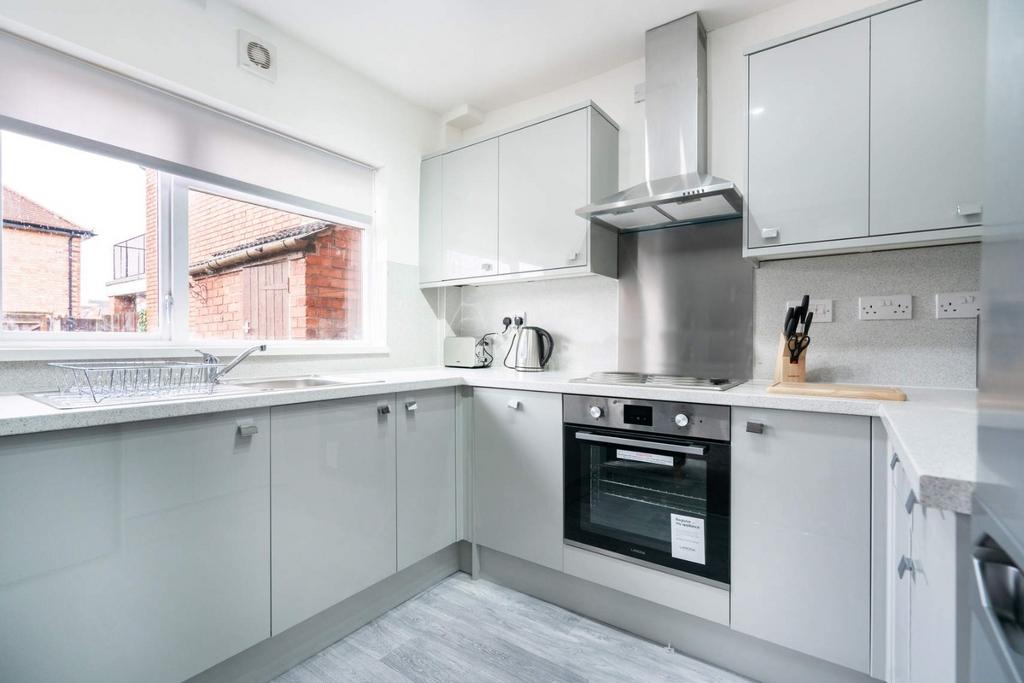 Bright modern fitted kitchen with integrated ov...
