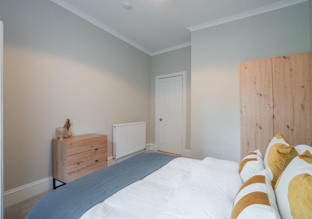 Bright, neutral double bedroom with simple wood...