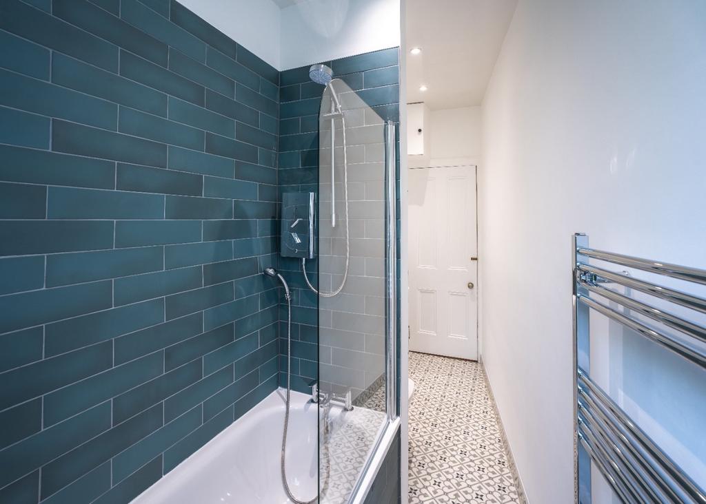 Modern bathroom with tiled bath and glass scree...