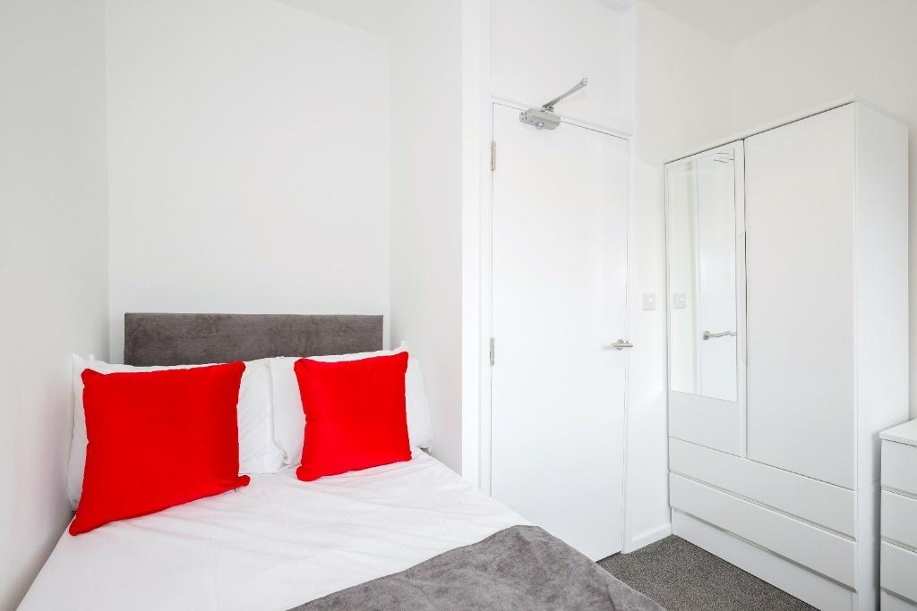 Bright, tidy bedroom with bold accent cushions...
