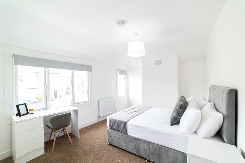 Bright bedroom with desk and large window...