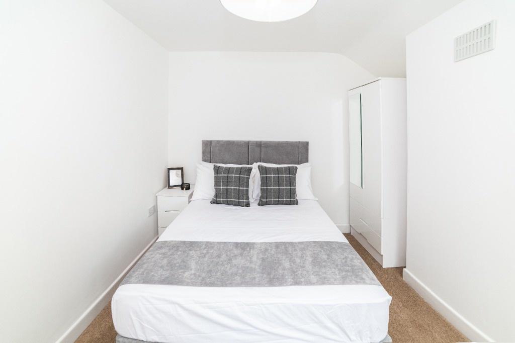 Bright, simple bedroom with double bed and stor...