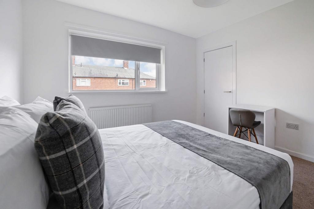 Bright, modern bedroom with desk and large wind...