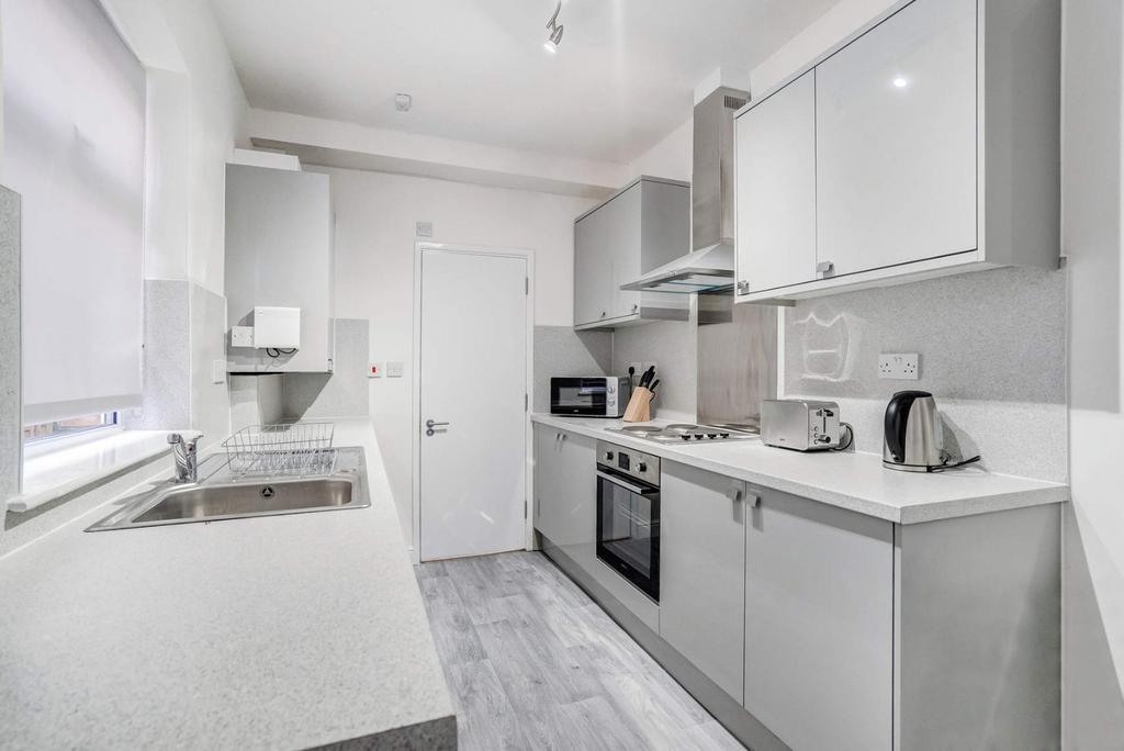 Bright modern galley kitchen with integrated ov...