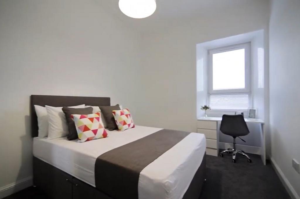 Bright, tidy bedroom with desk and modern bed...