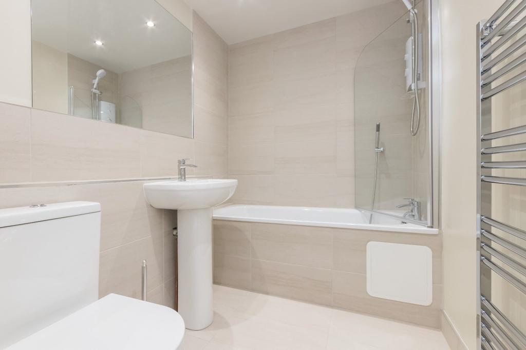 Modern neutral bathroom with bath and tiled wal...