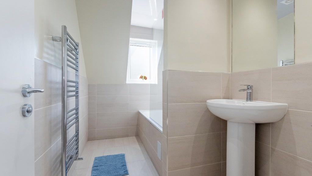 Bright modern bathroom with bathtub and towel r...