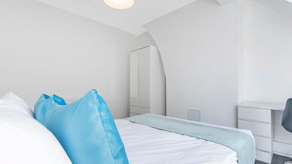 Bright, neat bedroom with crisp linens and desk...