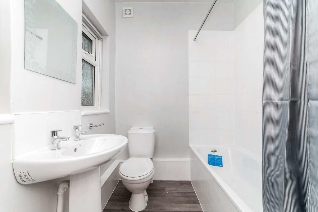 Bright modern bathroom with shower over bath...