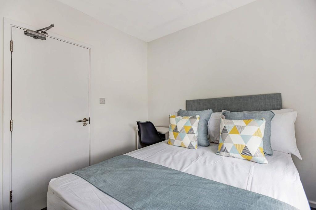 Bright, neatly made bedroom with modern bedding...