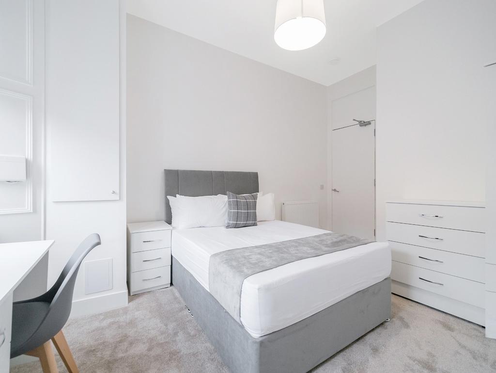 Bright, tidy bedroom with bed and desk...