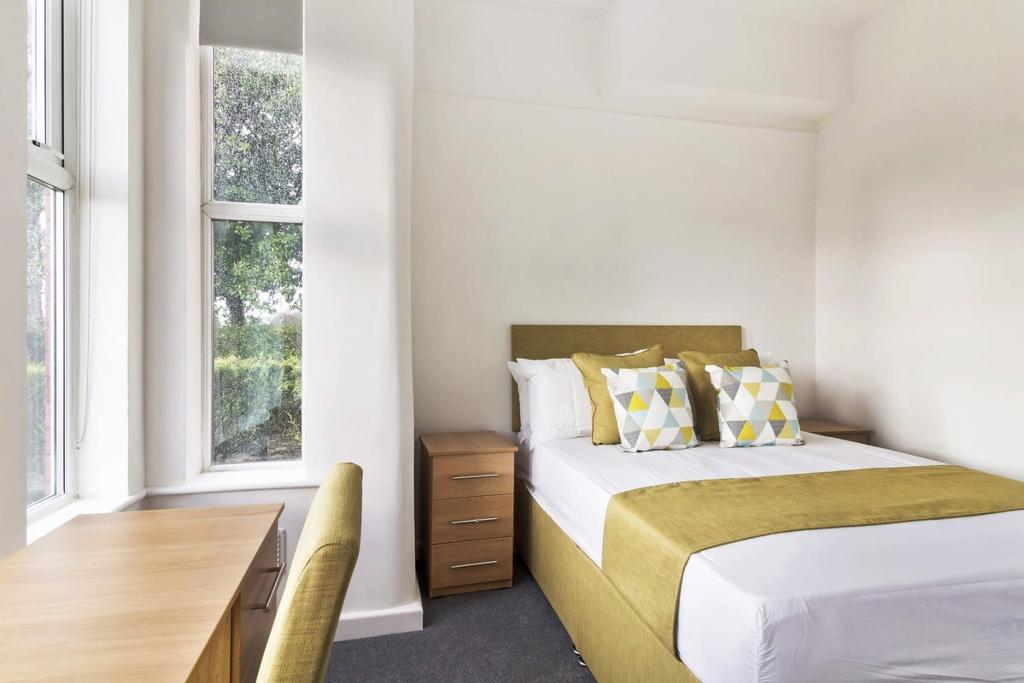 Bright, tidy bedroom with study desk and comfor...
