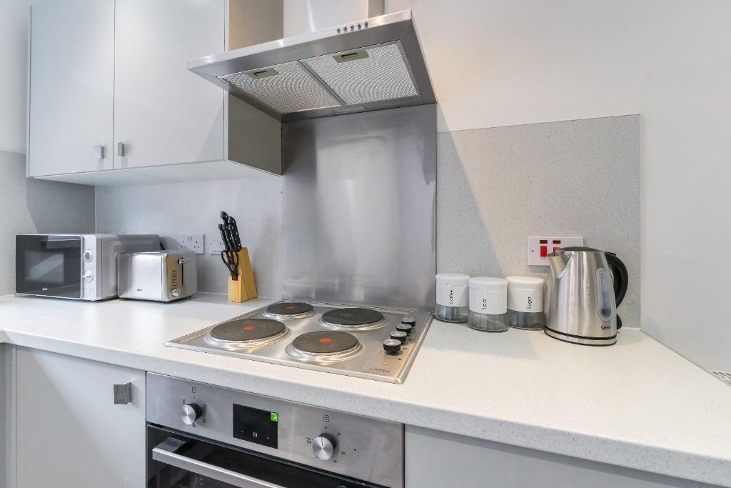 Modern compact kitchen with white units and hob...