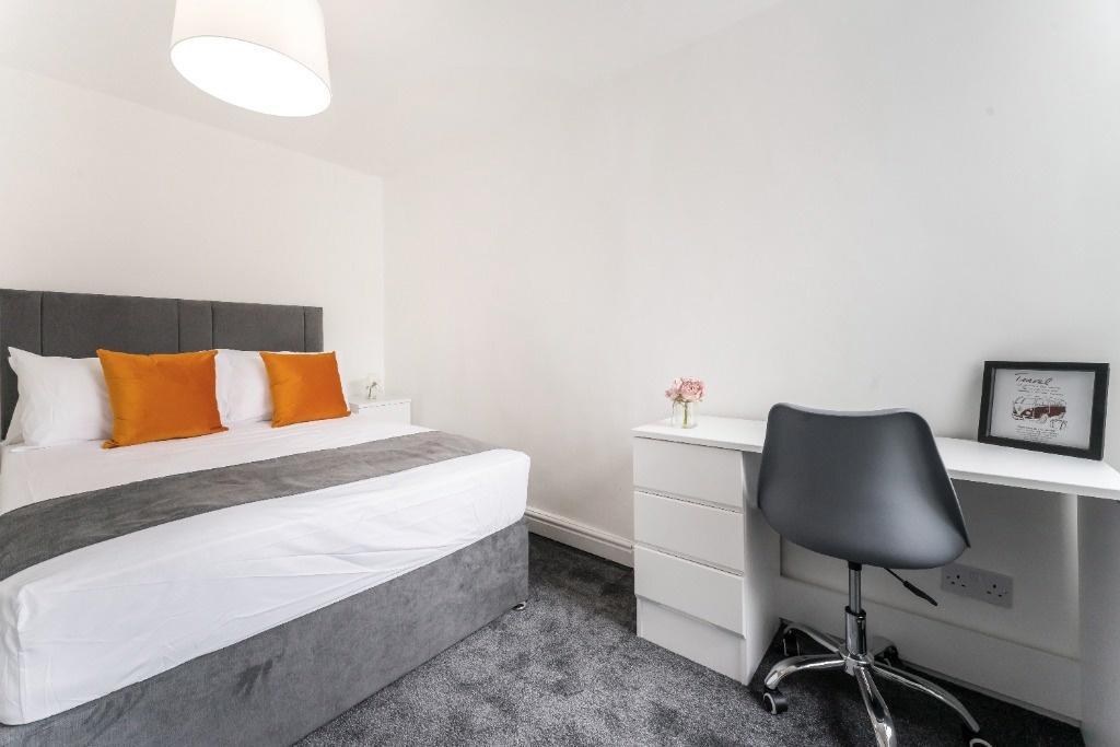 Bright, modern bedroom with desk and storage...