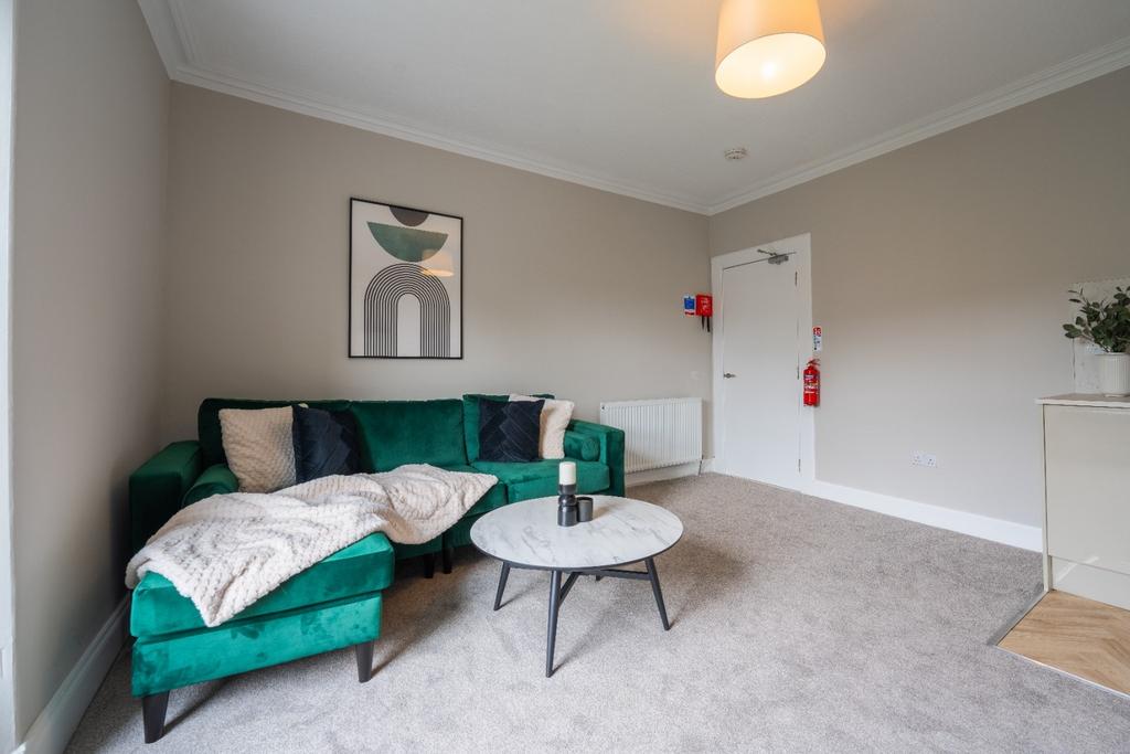 Bright, modern living room with green sofa...