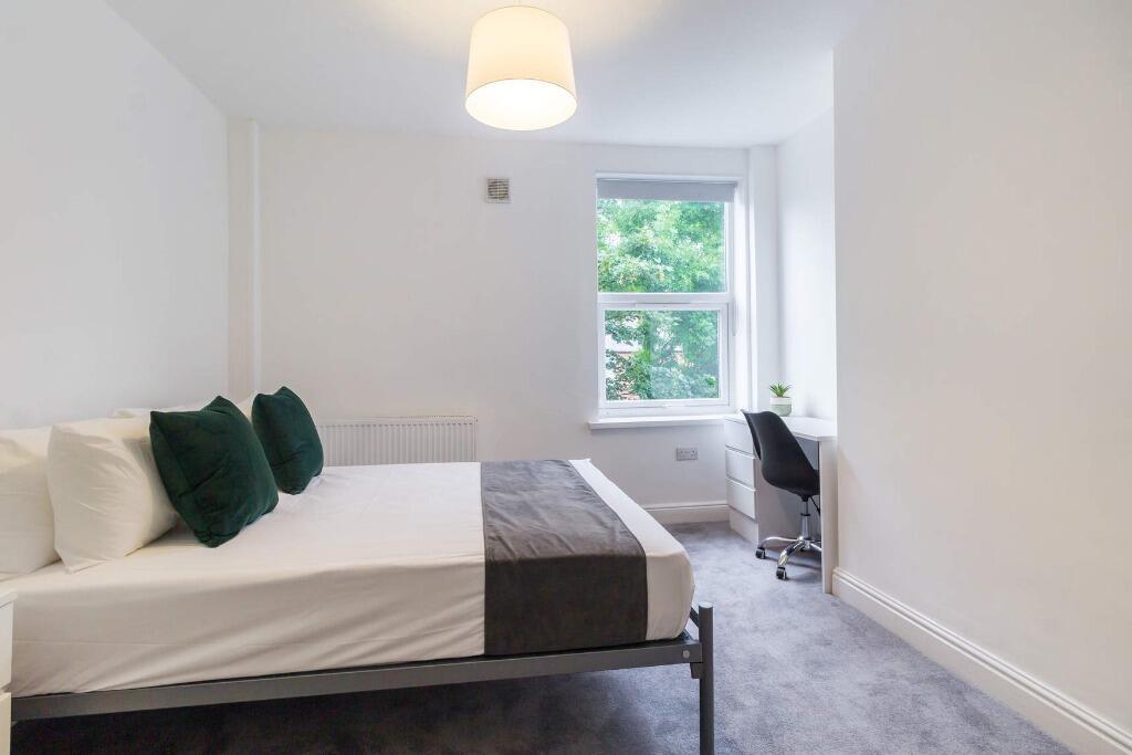 Bright, tidy bedroom with study space and green...