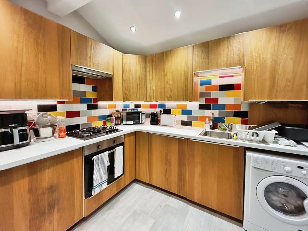 Modern fitted kitchen with colourful tiled spla...
