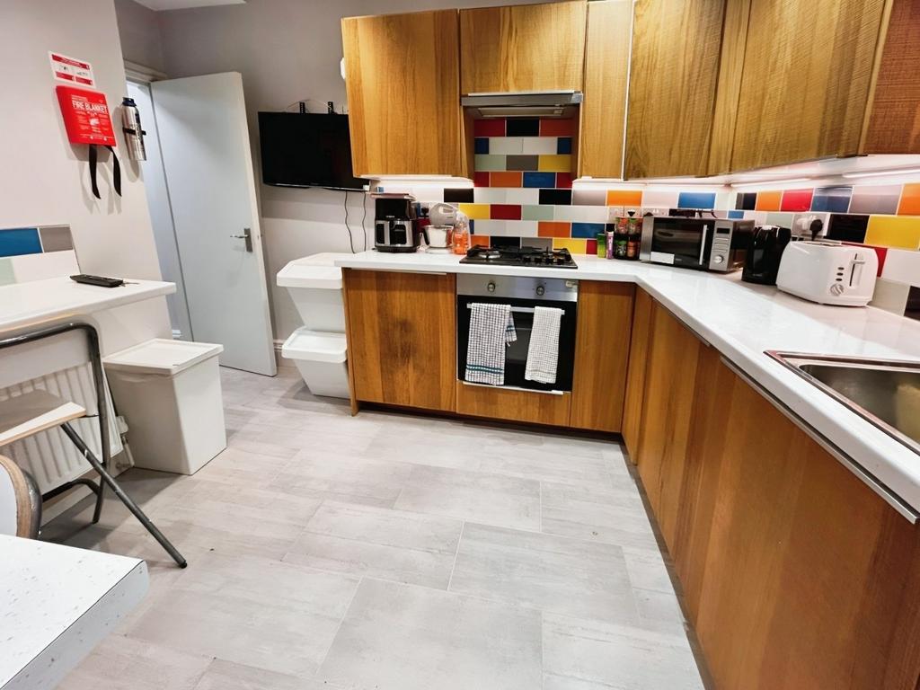 Modern fitted kitchen with wood cabinets and ti...
