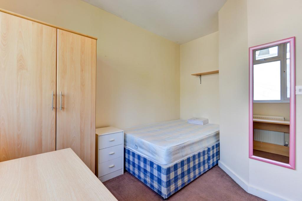 A tidy student bedroom featuring a single bed w...