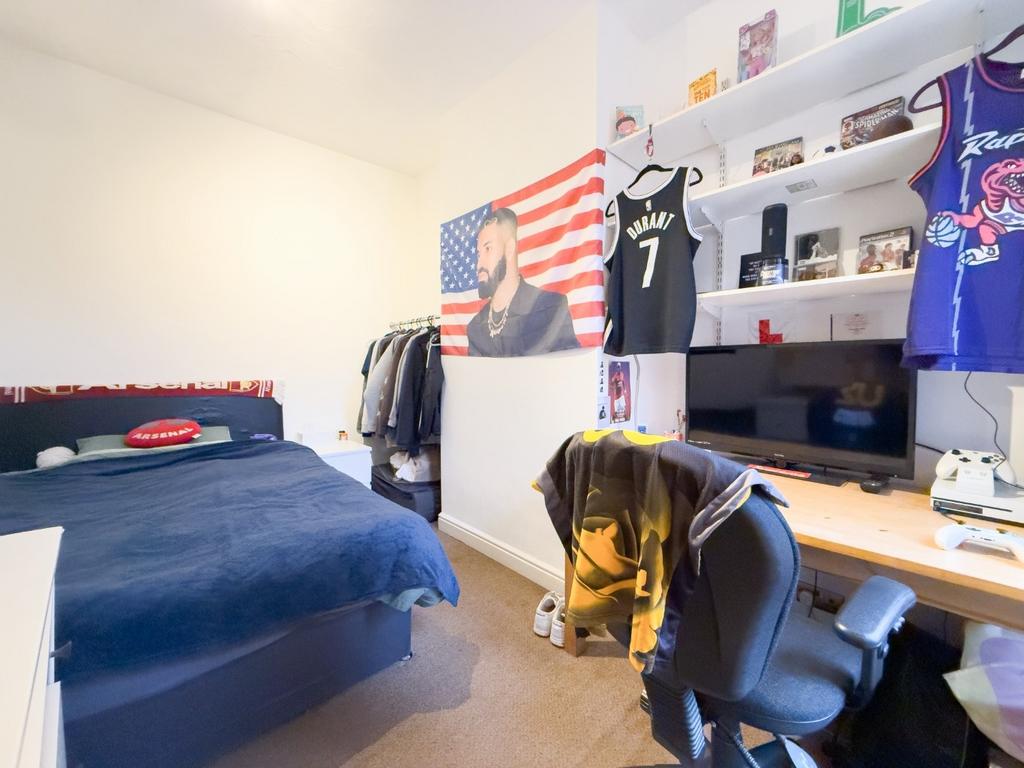 Bright furnished bedroom with desk and shelving...
