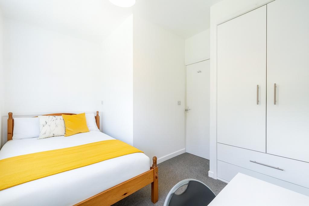 A bright and clean single bedroom featuring a w...