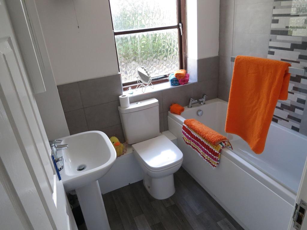 Bright and clean bathroom featuring a bathtub w...