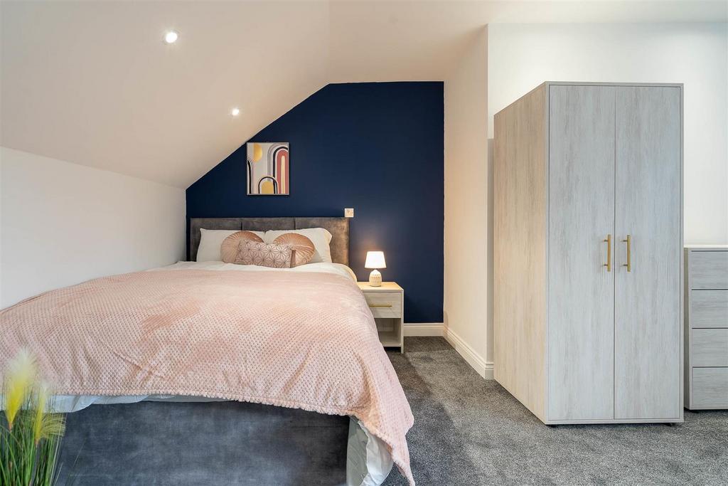 Cosy double bedroom with stylish navy accent wa...