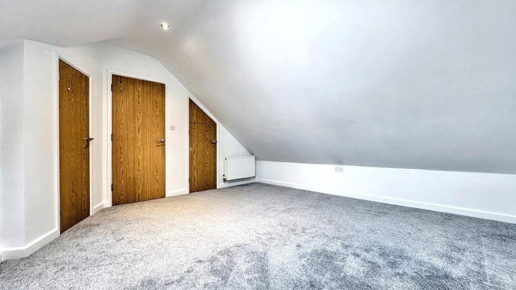 Bright attic bedroom with neutral carpet...
