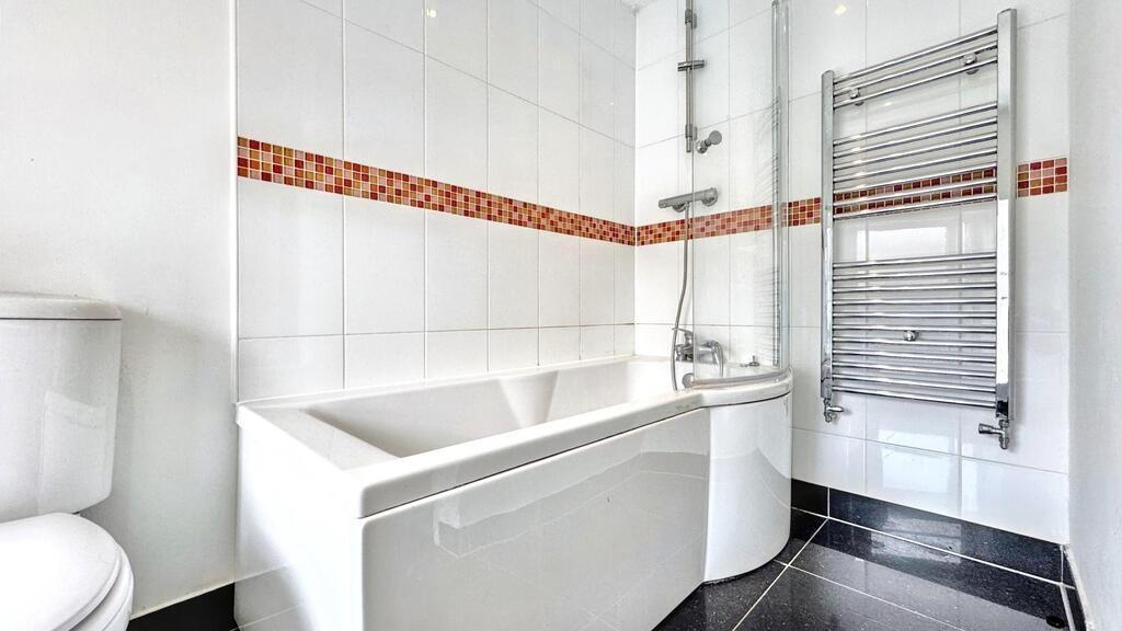 Bright modern bathroom with white tiles and hea...