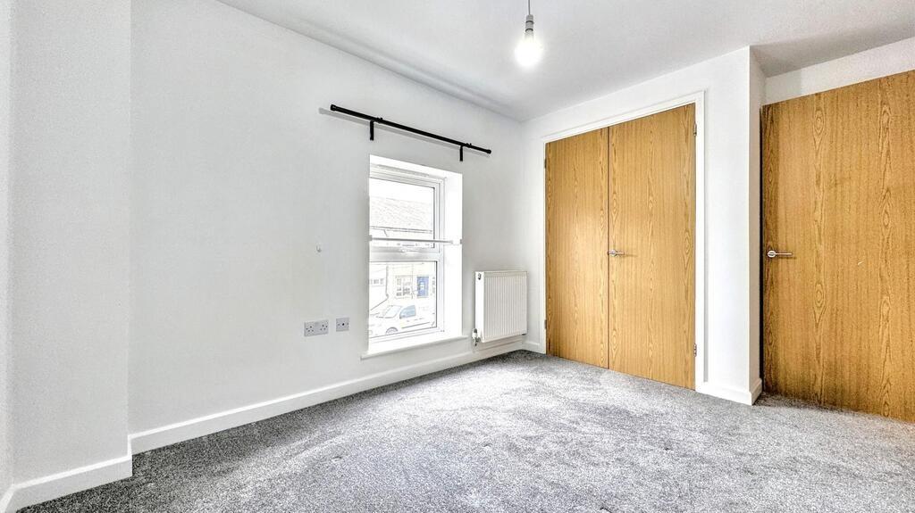 Bright bedroom with built-in wardrobes and wind...