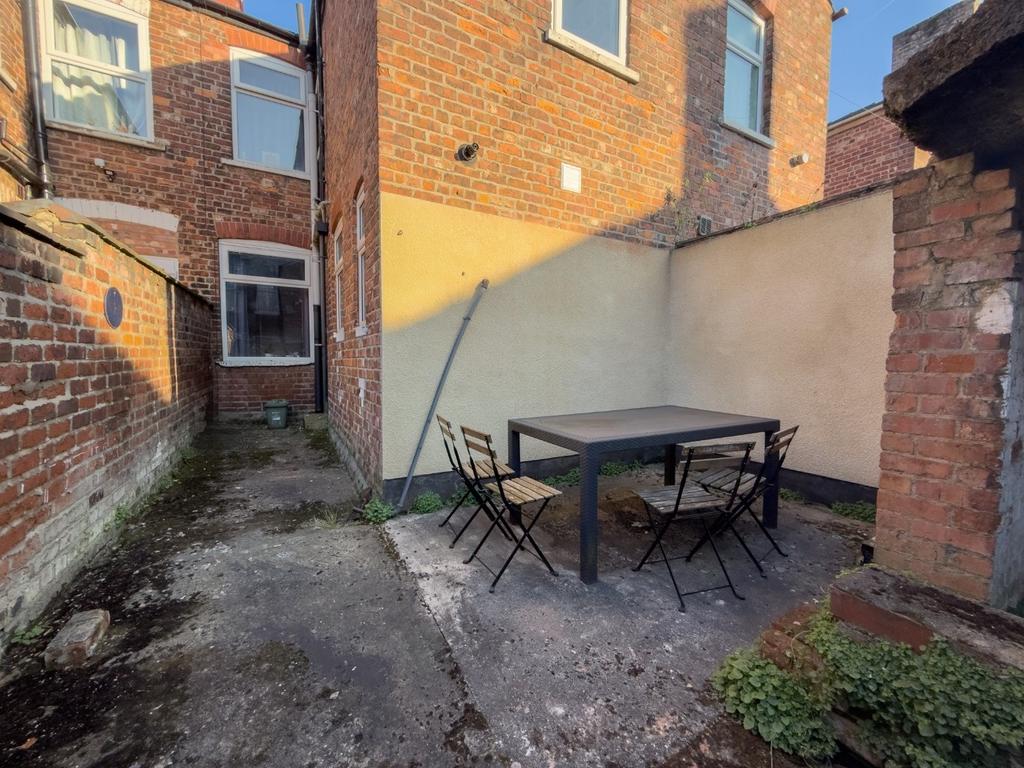 Private paved rear yard with outdoor seating...