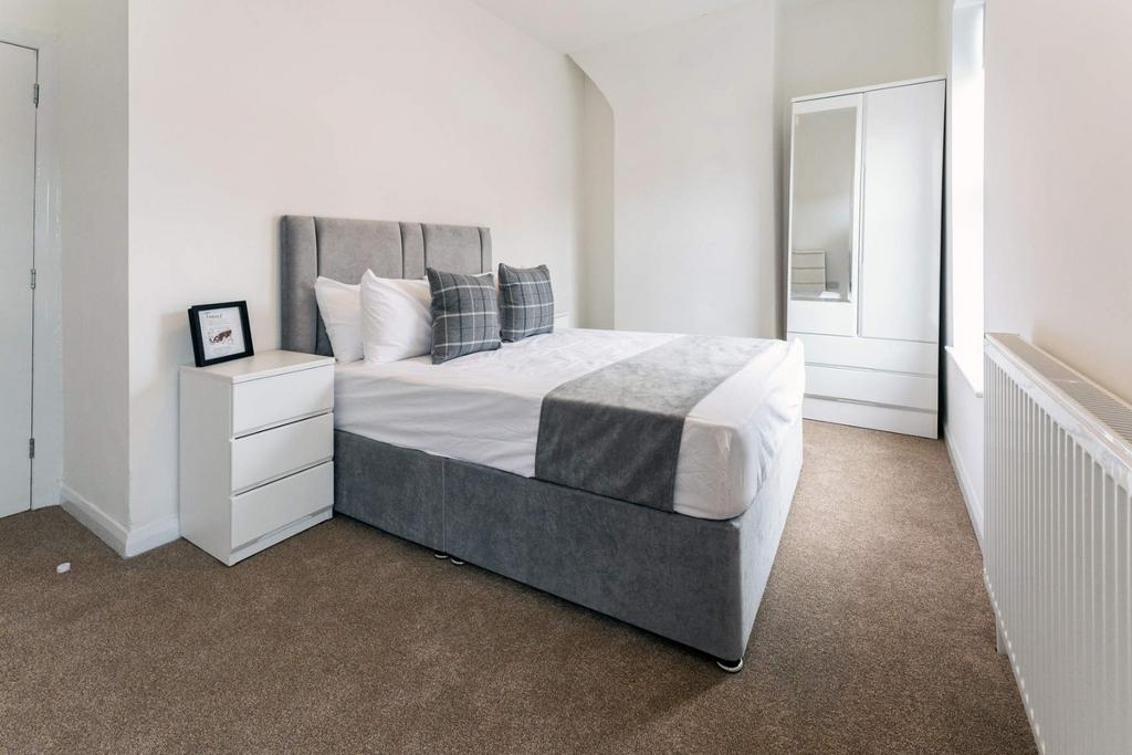 Bright, tidy bedroom with modern bed and storag...