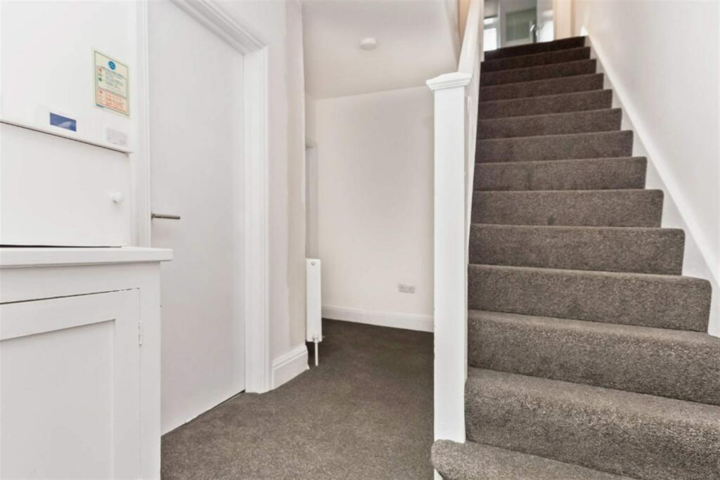 Clean, neutral hallway with carpeted stairs...