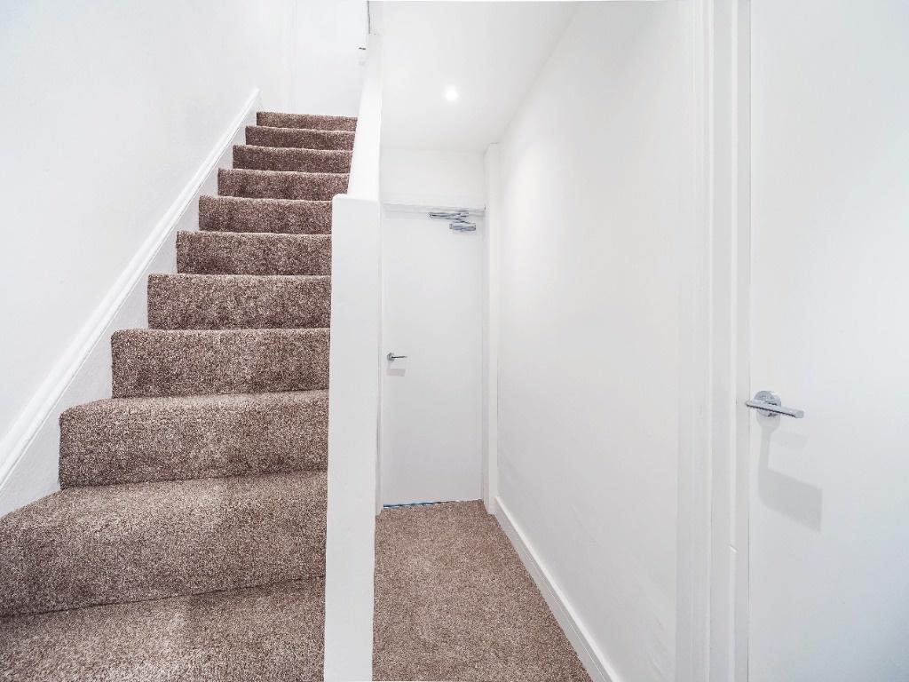 Bright entrance hallway with carpeted stairs...